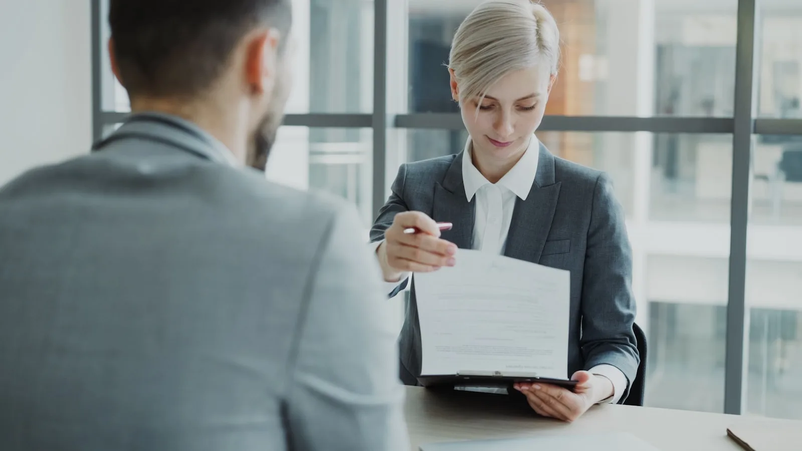 Colloquio di lavoro in ufficio con responsabile HR che mostra un documento a un candidato