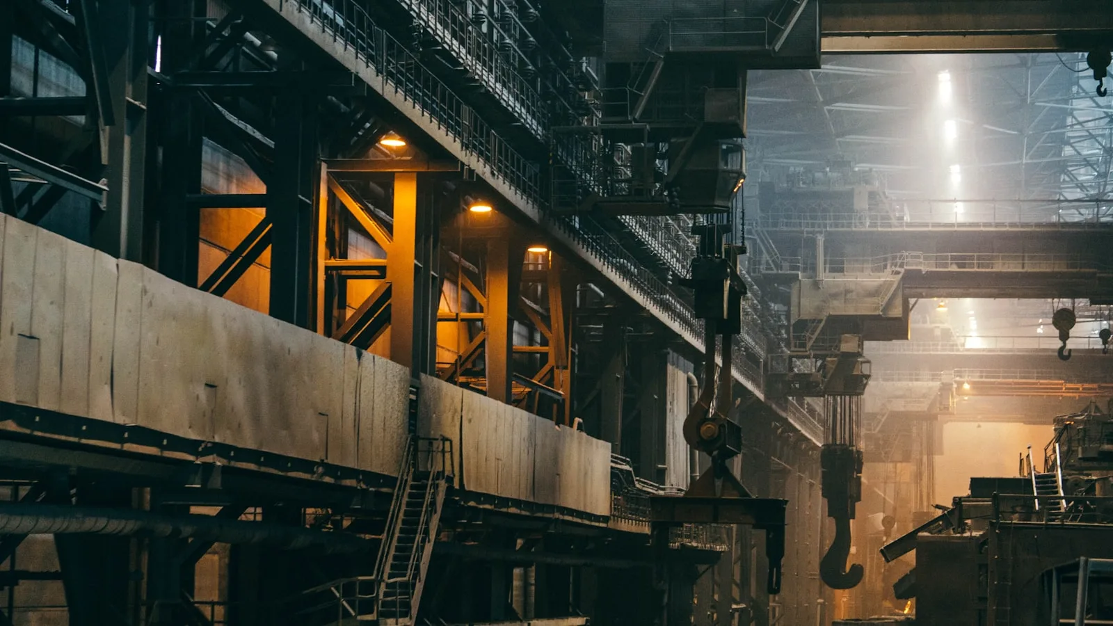 Interno di un grande impianto industriale con strutture metalliche e gru