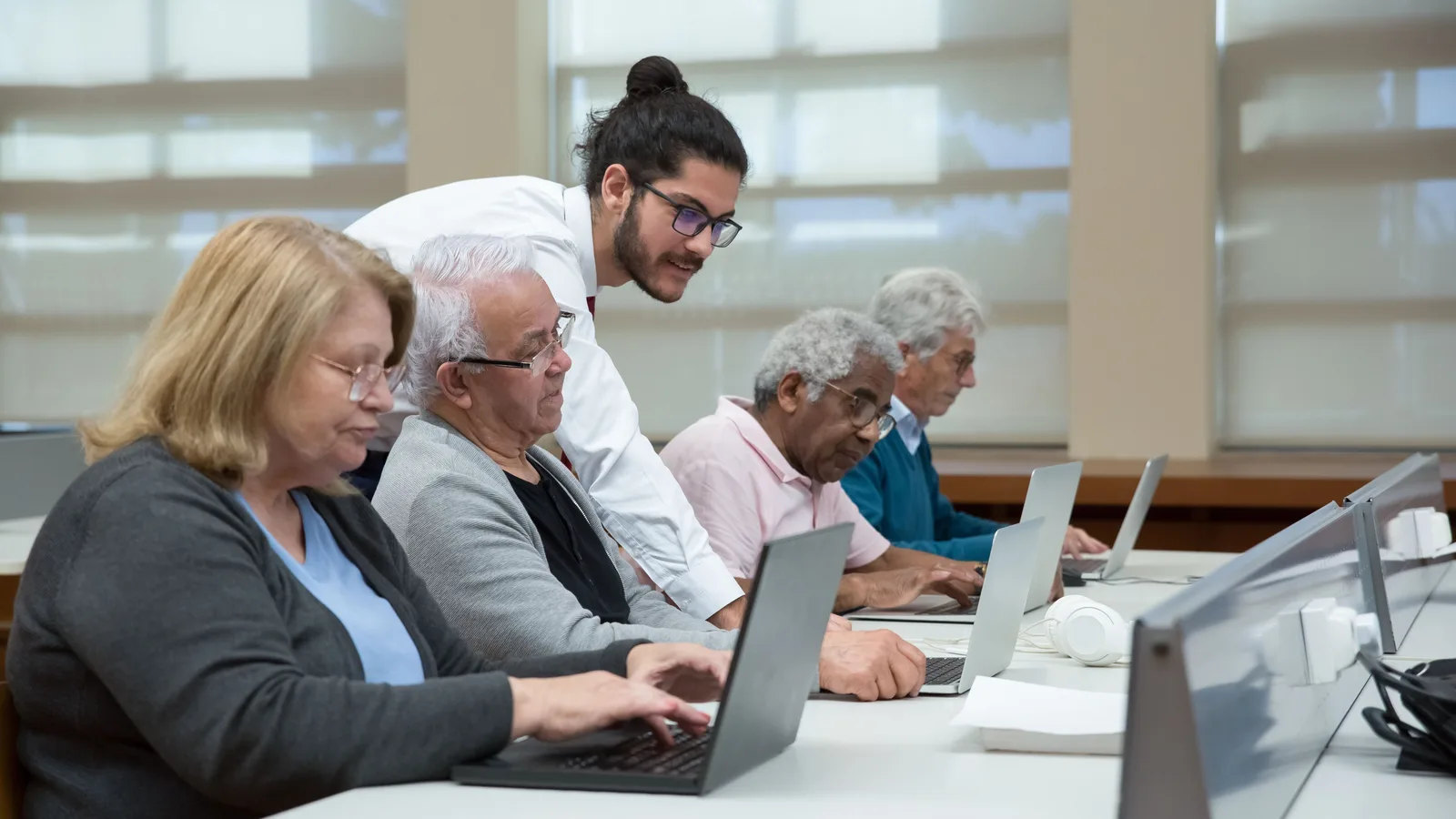 Adulti in aula seguono una formazione digitale con computer portatili